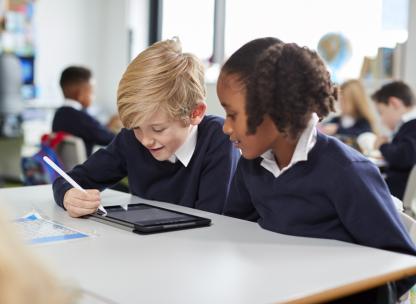 Two young pupils working on an ipad in a school