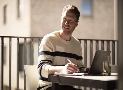 Man sat in an outdoor space, working on his laptop at The Icon development
