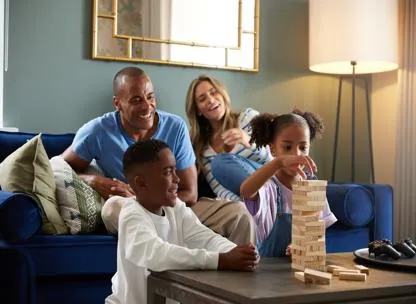 Parents and two children sat in a lounge at Timber Works development playing with wooden blocks