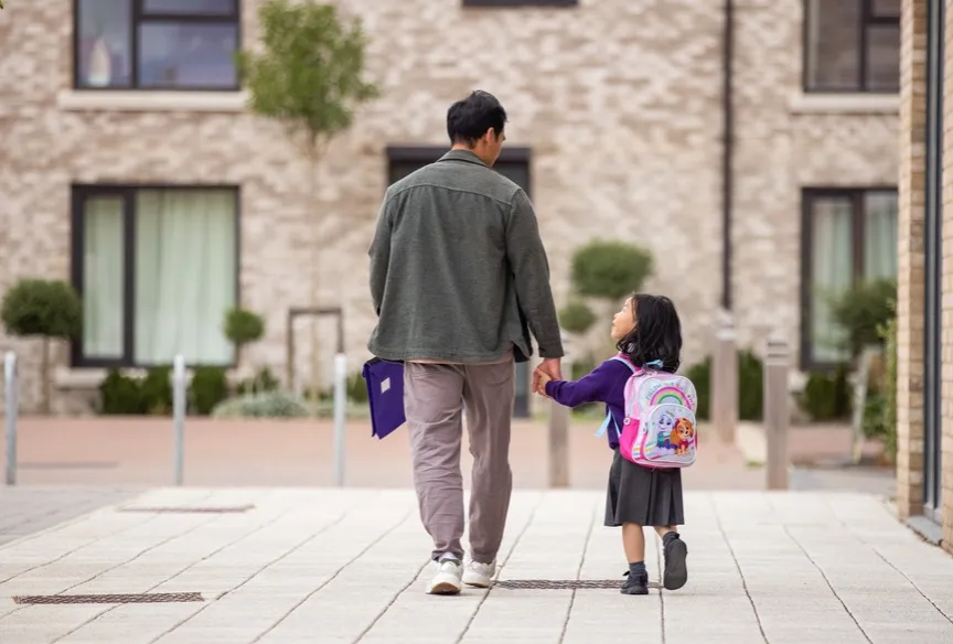 Man walking with his small child wearing a backpack on way to school