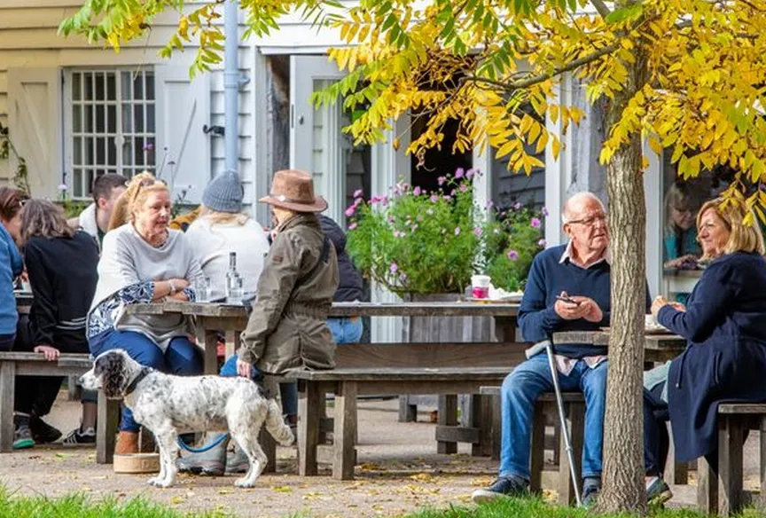 Exterior of a pub lined with benches and people enjoying a drink