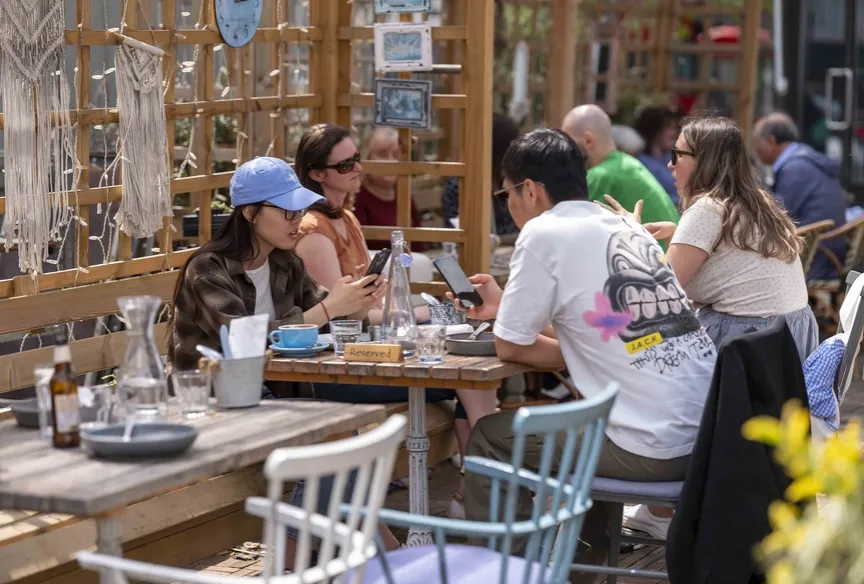 Groups of young people sat outside at a cafe in London