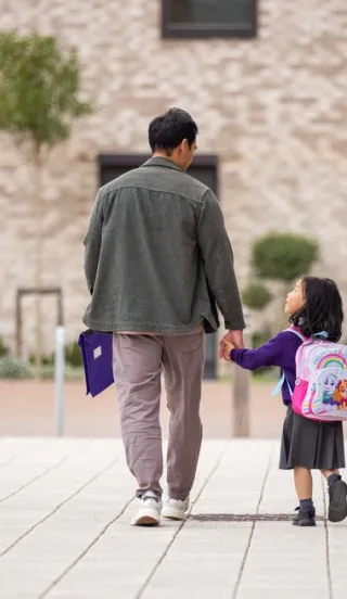 Man walking with his small child wearing a backpack on way to school