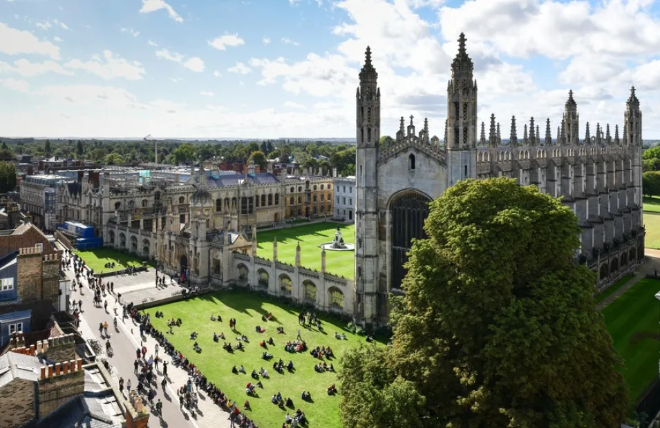 Aerial view of Cambridge university surrounded by people sat on the fields