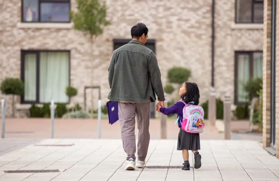 Man walking with his small child wearing a backpack on way to school