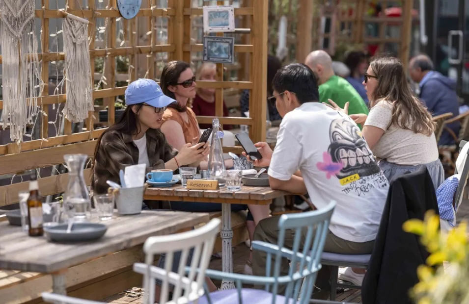 Groups of young people sat outside at a cafe in London