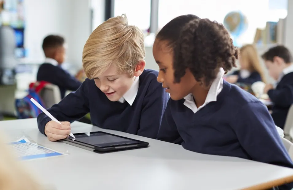 Two young pupils working on an ipad in a school